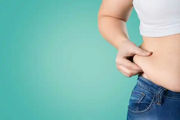 Image of woman pinching her love handles to show weight gain Welwyn Garden City